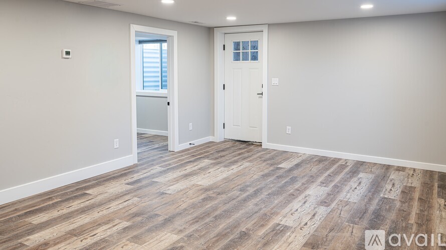 A room with wooden flooring and two doors, one of which is open.