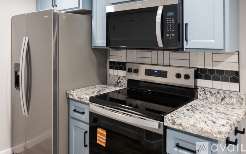 A kitchen with a refrigerator, microwave, and oven.