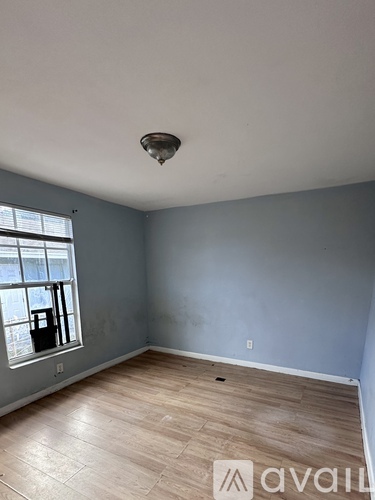 A room with a window and a wooden floor.