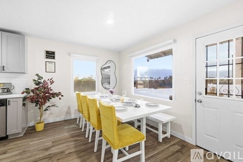 A dining room with a white table and yellow chairs.