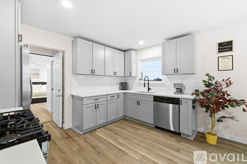 A kitchen with a stove top oven and a plant in a yellow pot.