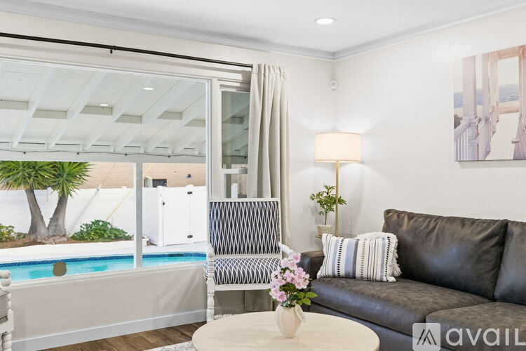 A living room with a couch, a chair, and a table with flowers on it.