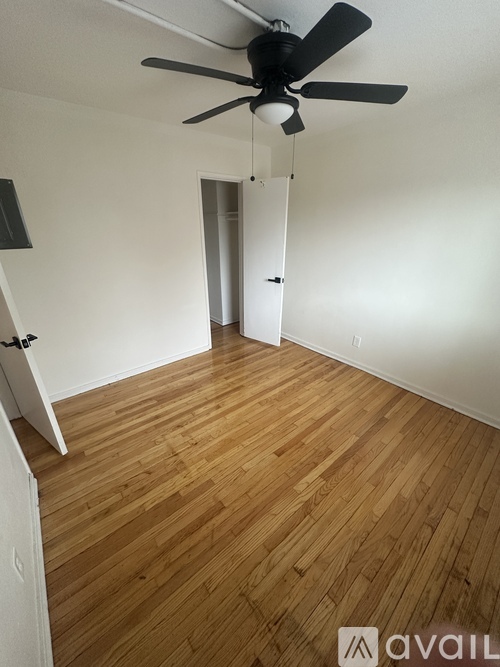A room with a ceiling fan and wooden flooring.
