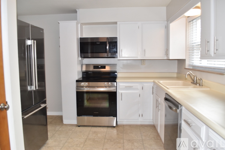 A kitchen with white cabinets and a black refrigerator.