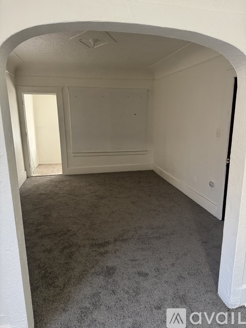 A carpeted room with a white archway leading to another room.
