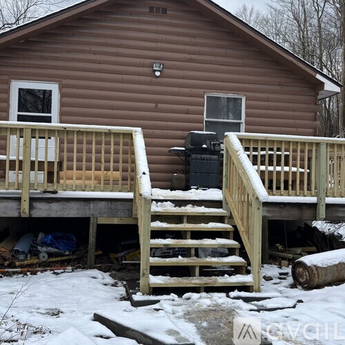 A brown house with a wooden deck in the snow.