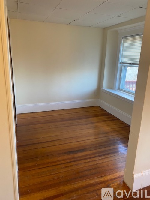 A room with wooden floors and a window with blinds.