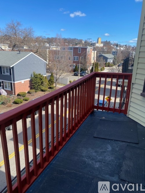 A red railing on a balcony with a view of a residential area.