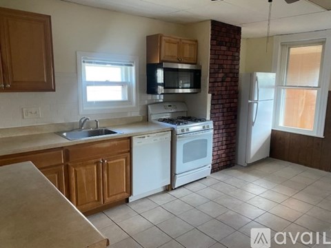 A kitchen with brown cabinets and a white stove top oven.