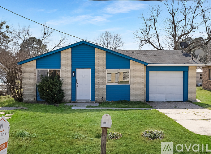 A blue and beige garage with a white door and a green dumpster.