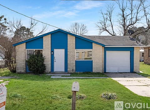 A blue and beige garage with a white door and a green dumpster.