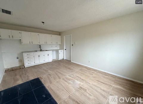 A kitchen with white cabinets and a black mat on the floor.