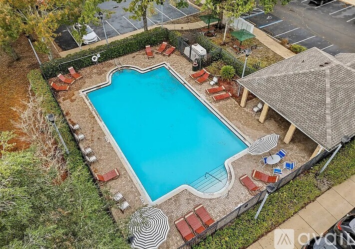 An aerial view of a pool surrounded by a brick wall and lounge chairs.