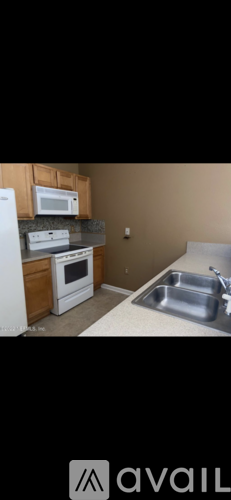 A kitchen with a white refrigerator, a white stove, a white microwave, and a stainless steel sink.