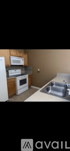 A kitchen with a white refrigerator, a white stove, a white microwave, and a stainless steel sink.