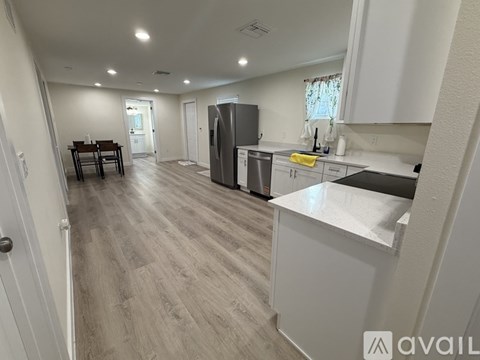 A kitchen with a refrigerator, sink, and dining table.