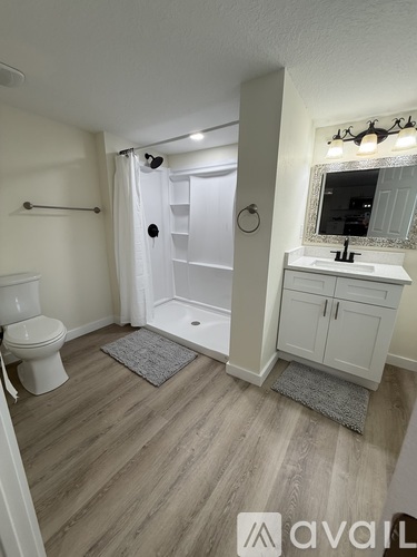 A bathroom with a toilet, sink, and shower.