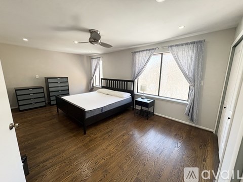 A bedroom with a large bed and a ceiling fan.