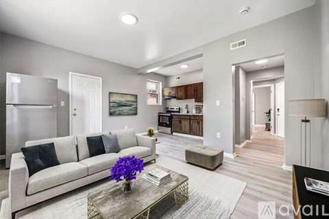 A modern living room with a grey couch and a coffee table with a vase of purple flowers on it.
