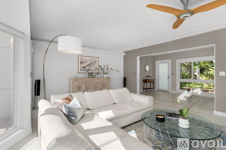 A living room with a white couch and a glass coffee table.