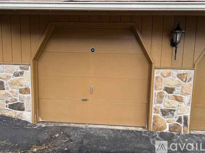 A tan garage door with a stone pillar on each side.