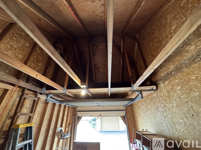 A room under construction with exposed wooden beams and insulation on the walls.