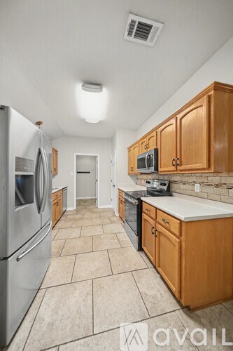 A kitchen with wooden cabinets and a tiled floor.