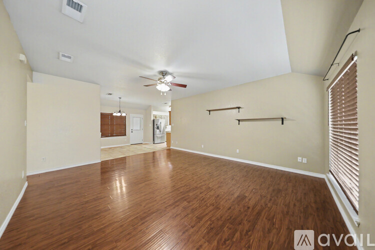 A spacious room with wooden flooring and a ceiling fan.