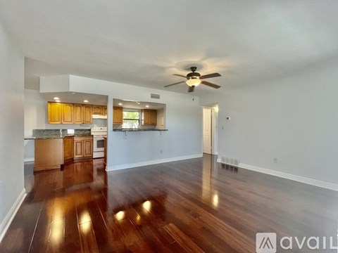 A spacious living room with hardwood floors and a ceiling fan.