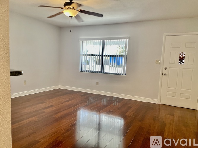 A room with a ceiling fan and wooden flooring.
