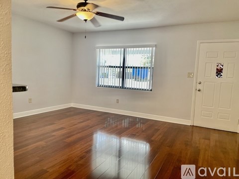 A room with a ceiling fan and wooden flooring.