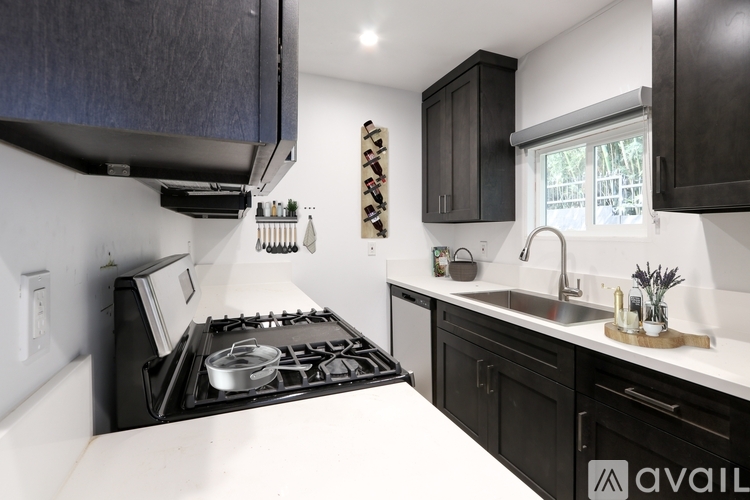 A modern kitchen with black cabinets and a white countertop.