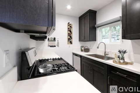 A modern kitchen with black cabinets and a white countertop.