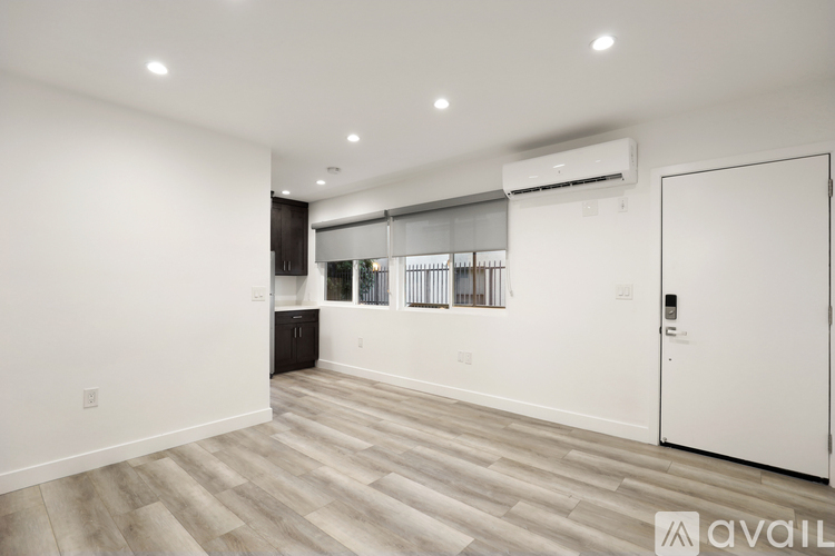 A spacious room with a white door and a window with blinds.