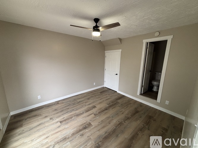 A room with a ceiling fan and wooden flooring.