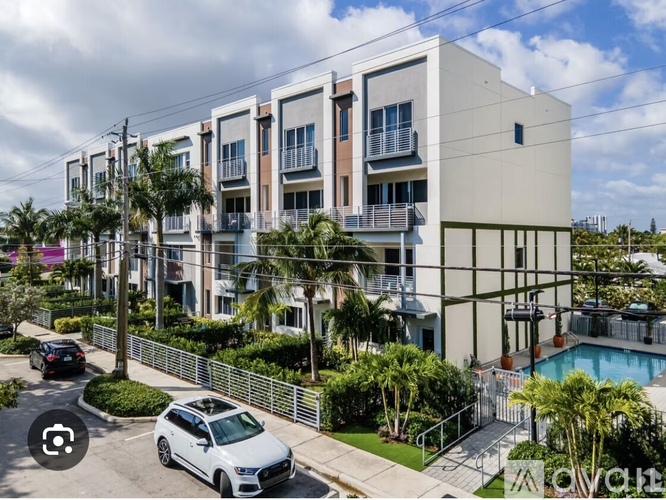 A white car is parked in front of a building with a pool.