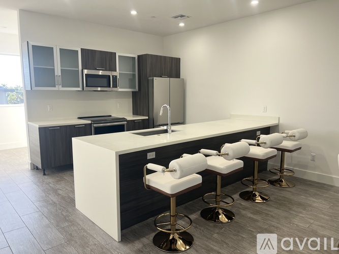 A modern kitchen with white countertops and bar stools.