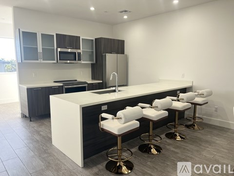 A modern kitchen with white countertops and bar stools.