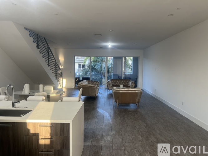 A modern kitchen with a bar area and a living room with a couch and chairs.