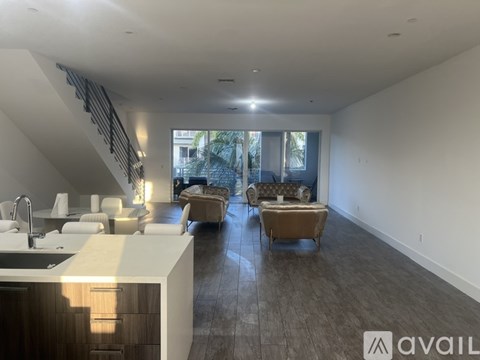 A modern kitchen with a bar area and a living room with a couch and chairs.