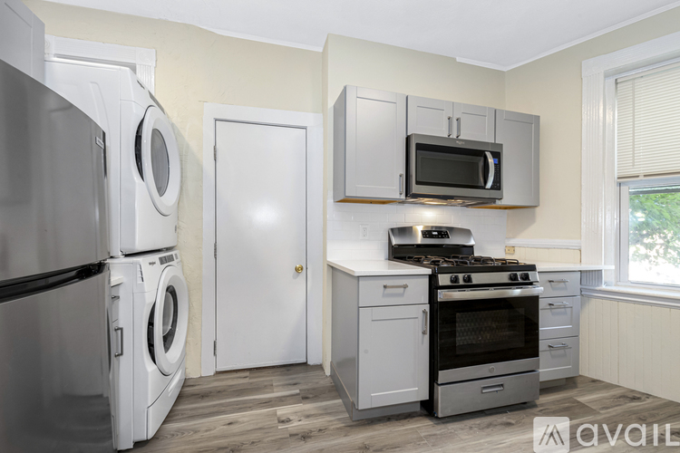 A kitchen with a refrigerator, washer, oven, microwave, and a window.