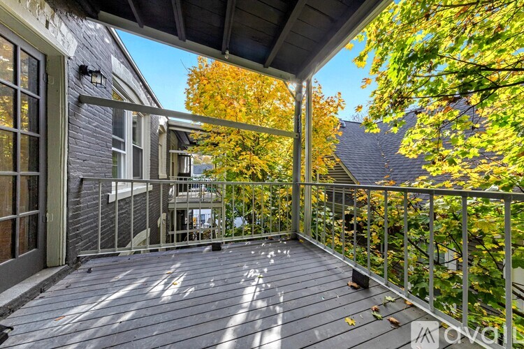 A wooden deck with a metal railing and trees in the background.