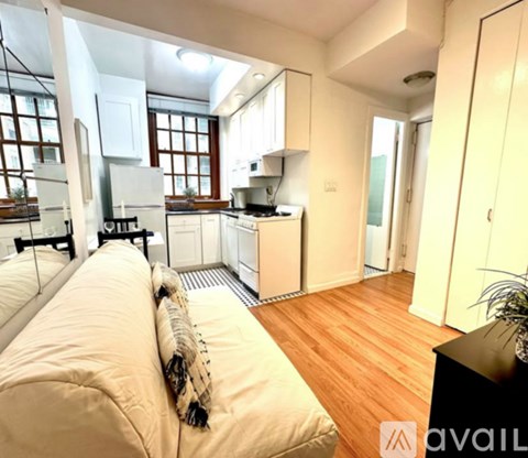 A well-lit kitchen with wooden floors and a large window.
