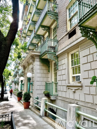 A street view of a building with balconies and potted plants.
