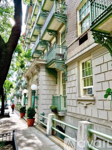 A street view of a building with balconies and potted plants.