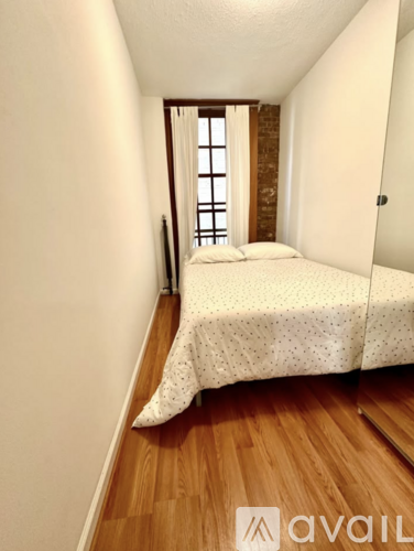 A bedroom with a bed and a window with a view of a brick wall.