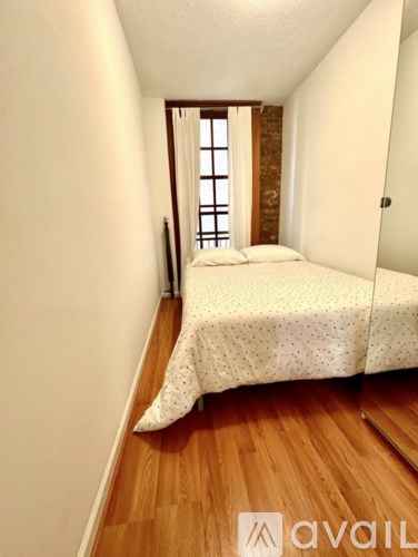 A bedroom with a bed and a window with a view of a brick wall.