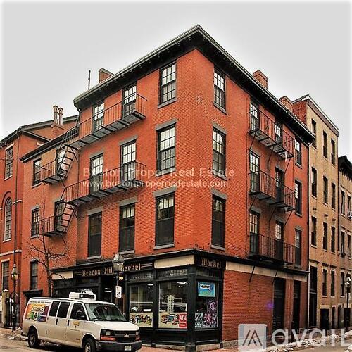 A red brick building with a white van parked in front.