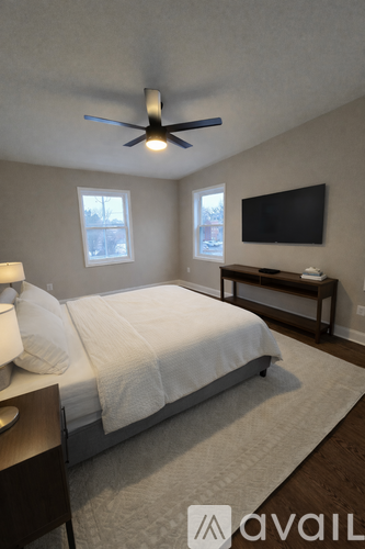 A bedroom with a bed, a ceiling fan, and a television.