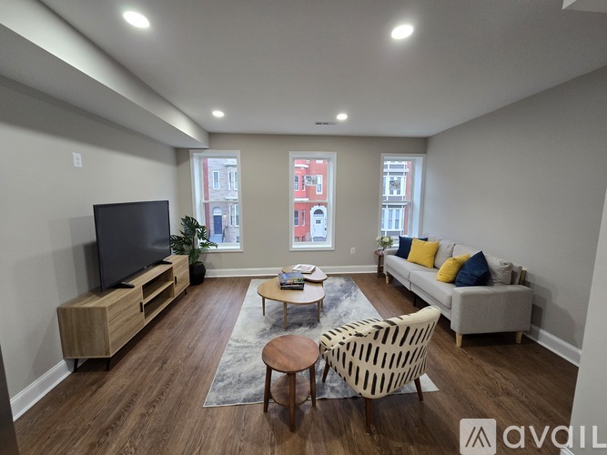 A living room with a television, couch, and chairs.